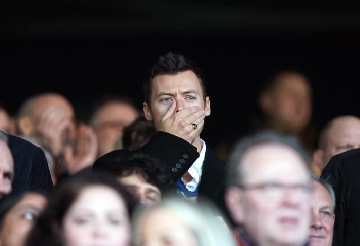 Harry Styles pictured covering his mouth with his hand while watching the Premier League game between Luton Town and Manchester United at Kenilworth Road in February 2024